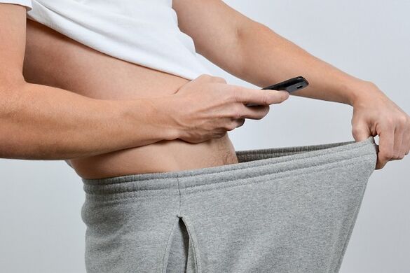 muškarac gleda kroz svoje hlače u povećani penis